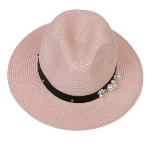 Détail du chapeau de paille rose avec ruban noir, perles blanches et fleur décorative