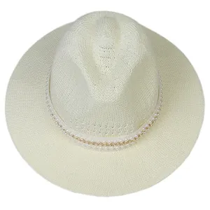 Detail of a creamy white woven sun hat featuring elegant faux pearl and gold chain trim
