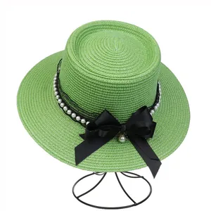 Detail of green straw hat featuring black lace, pearls and large satin bow decoration