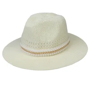 Detail of cream straw fedora hat featuring elegant pearl and gold chain decoration