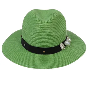 Détail du chapeau de paille vert avec ruban noir orné de perles et de fleurs