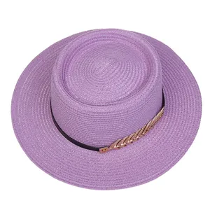 Detailed top view of purple straw sun hat with black band and golden feather ornament