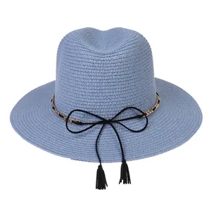 Detail of light blue woven sun hat featuring a metal chain and black ribbon with tassels