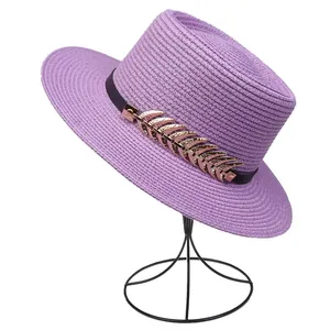 Detailed texture of purple straw hat with gold feather buckle and black ribbon trim