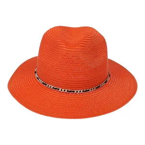 Close-up of orange straw fedora hat featuring a gold chain and black woven trim detail