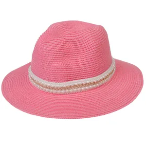 Détail d'un chapeau de paille rose avec dentelle blanche, perles et chaîne dorée
