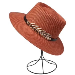 Detail of vintage burnt orange straw sun hat featuring a gold leaf metal ornament