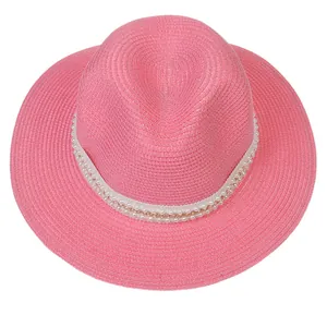 Détail d'un chapeau Panama rose avec texture tissée et garniture en perles et chaîne d'or