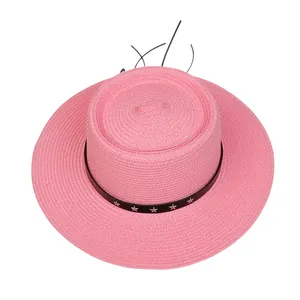 Detailansicht eines rosa Strohhutes mit schwarzem Sternenband und flachem Design