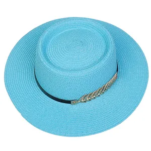 Detail view of sky blue straw boater hat with black ribbon and gold metal leaf charm
