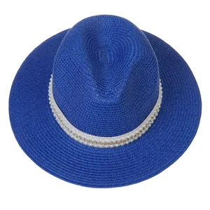 Détail d'un chapeau Panama bleu en paille avec ruban orné de perles et chaîne dorée