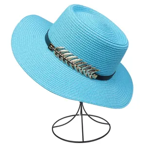 Detail of blue straw hat featuring black ribbon and golden leaf metal ornament