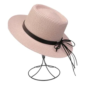 Detailansicht eines rosa Strohhuts mit schwarzer Schleife auf minimalistischem Hutständer