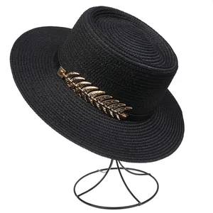 Detail of black woven boater hat featuring elegant gold leaf metal accent and grosgrain ribbon