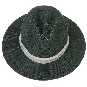 Détail du tissage en paille avec ruban blanc orné de perles et d'une chaîne dorée
