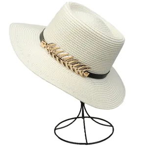 Detail of cream straw hat with black band and golden leaf metallic embellishment