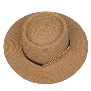 Top-down view of woven straw hat with black leather band and gold chain decoration