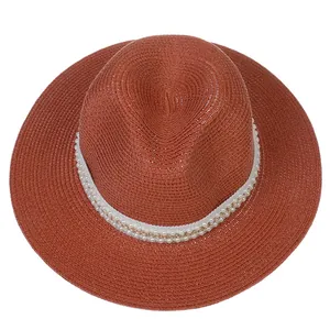 Détail du chapeau Panama terracotta avec ruban élégant de perles et chaîne dorée