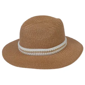 Détail d'un chapeau de paille marron avec ruban blanc orné de perles et chaîne dorée