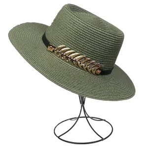 Close-up of dark green woven straw fedora featuring a gold leaf metal ornament accessory