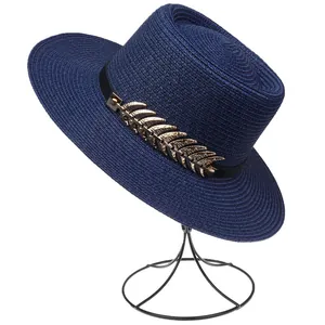 Detail view of navy blue woven sun hat with decorative golden metal leaves and black band