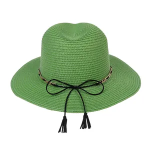 Detail of light green Panama hat with woven texture, black bow, and gold chain trim