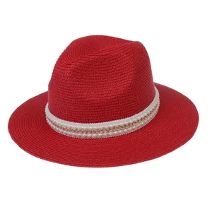 Détail du chapeau Panama rouge avec ruban blanc, chaîne dorée et décor de perles tressé