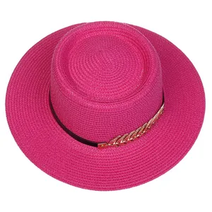 Detail of rose pink straw boater hat featuring gold leaf accent and black band