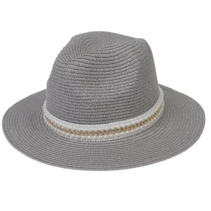 Détail du chapeau de paille gris avec décor de perles et chaîne dorée sur fond blanc