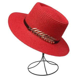 Detail of red straw sun hat with black ribbon and gold feather metal hardware