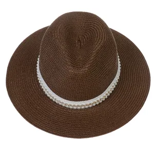 Détail du chapeau Panama avec ruban blanc décoratif, perles et chaîne dorée