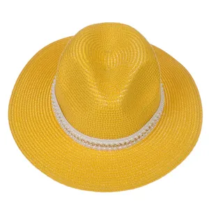 Détail du chapeau Panama jaune avec ruban décoratif en perles et chaîne dorée