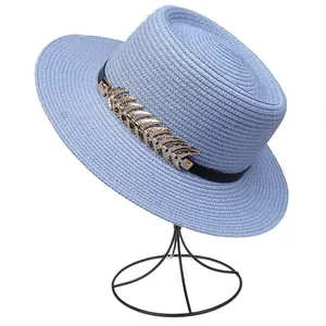 Detail of light blue straw hat with black band and golden metal leaf decoration