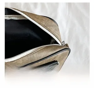 Detail view of the smooth top white zipper and black interior lining of this stylish bag
