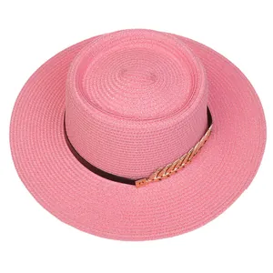 Detail of pink straw boater hat featuring gold wheat ear charms on a black band