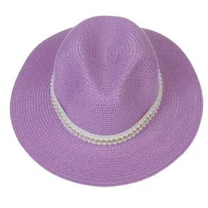 Détail d'un chapeau de paille violet avec texture tressée et chaîne de perles