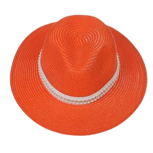 Détail d'un chapeau Panama orange orné d'un ruban décoratif perles et chaîne dorée