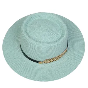 Top view of mint green straw boater hat with black ribbon and gold leaf ornament