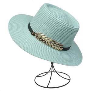 Detailed texture of light blue straw sun hat with gold leaf accents on a black display stand