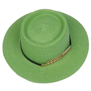 Detail of green straw boater hat with black band and golden leaf metallic ornament