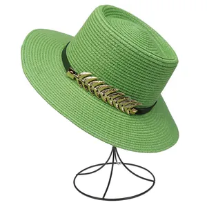 Macro detail of grass green straw hat featuring black band with golden leaf ornament