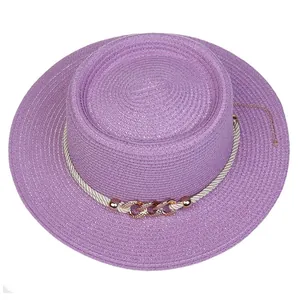 Detail of purple boater straw hat featuring white rope and rose gold chain ornament
