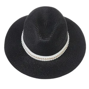 Détail chapeau Panama en paille noire avec ruban perlé et chaîne dorée élégante