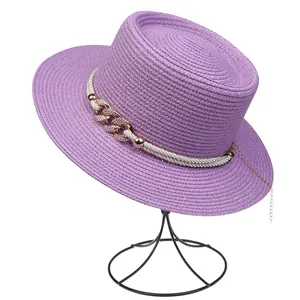 Detailed texture of purple straw hat with white rope and golden chain decorations