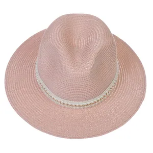 Détail d'un chapeau Panama rose avec ruban décoratif de perles et chaîne dorée