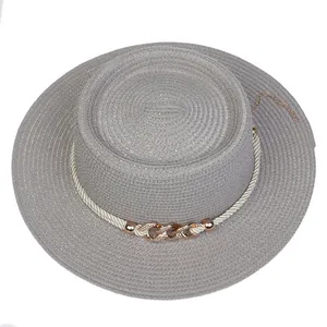 Detail view of grey woven straw hat with elegant rope and golden chain decoration