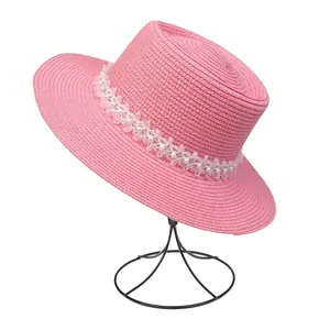 Detailansicht vom rosa Strohhut mit eleganter weißer Spitze und Perlenverzierungen
