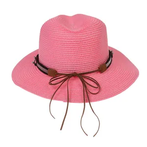 Détail du chapeau de paille rose avec ruban marron foncé et élément décoratif argenté