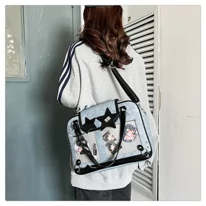 Detail of light blue ita bag with clear star window showing anime badges on shoulder