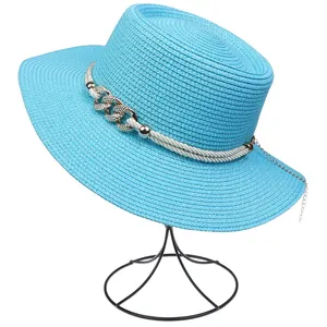 Detail of sky blue straw hat with elegant metal chain and white rope decor